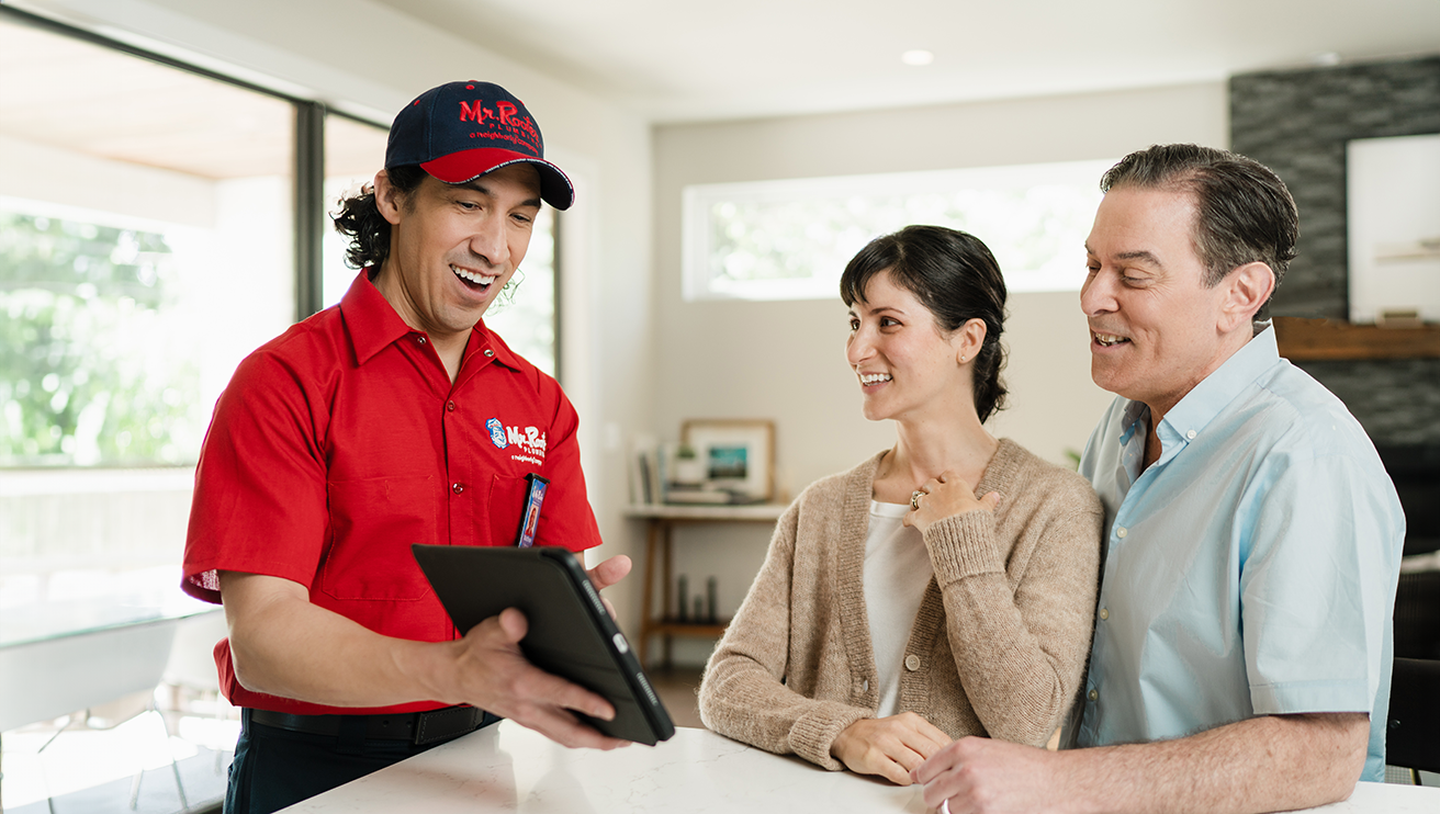 Mr. Rooter technician showing customers service options on a tablet.
