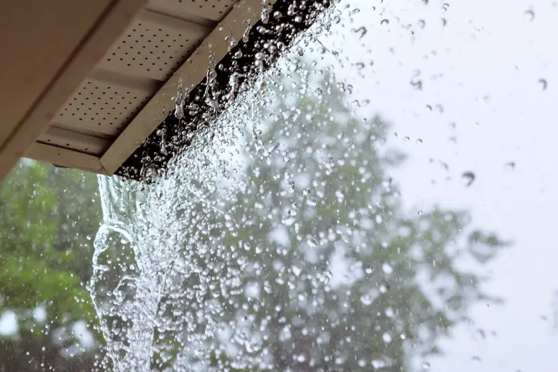Rainwater draining from residential gutters during a storm.
