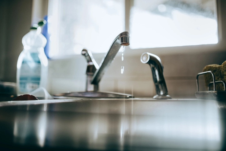 A close-up of a kitchen faucet with water dripping out, indicating a leak. | Mr. Rooter® Plumbing of South Jersey