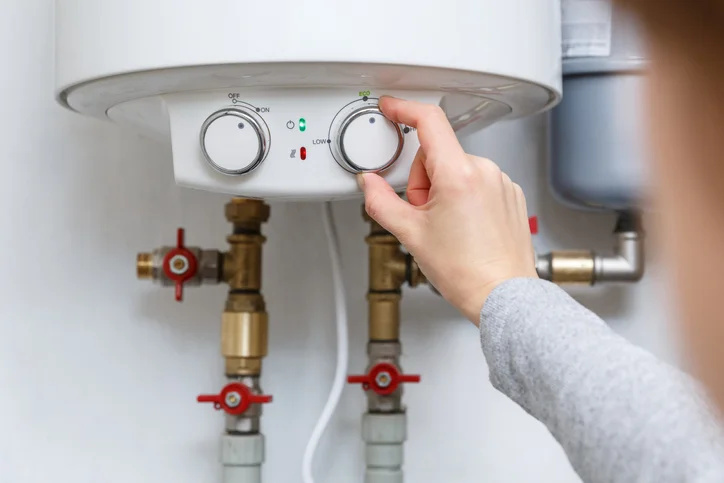 A woman&rsquo;s hand adjusts the dial on an electric water heater. | Mr. Rooter Plumbing of The Oakland-Berkeley Area